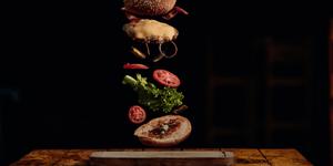 A photo of a hambuger with the parts floating in air