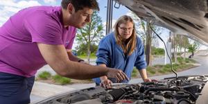 Instructor teaching a young woman to check her oil