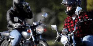 Two people on motocycles leaning to ride