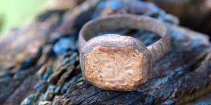 A very old metal ring sitting on a piece of slate rock.