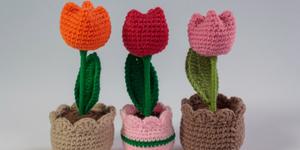 Three crocheted flowers orange, red, and pink.