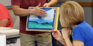 An instructor giving feedback to student on her landscape drawing.