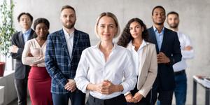 A diverse group of men and women in business attire smiling and ready to work.
